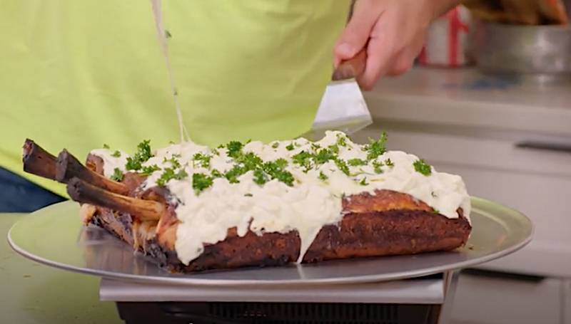 This photo shows a pizza with a crispy Detroit-style edge, short rib bones sticking out on one side and a ton of melted white cheese on top.