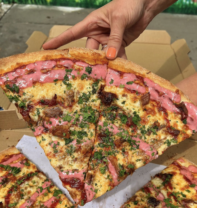 This photo shows a pizza ringed with a pinkish beet horseradish sauce and topped with brisket, mozzarella and havarti cheese.