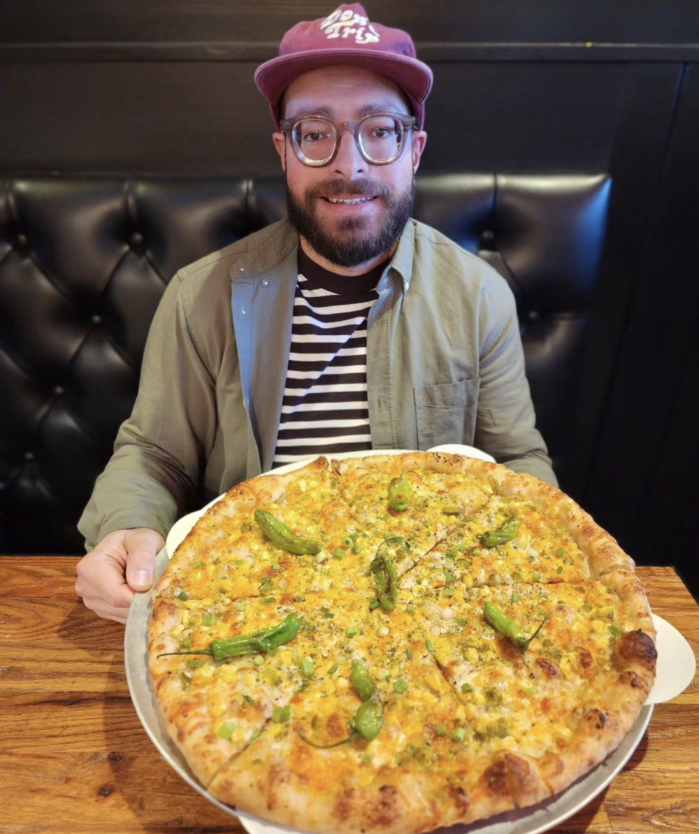 A picture of viral pizza chef Billy Zureikat holding his now-famous The Tripping Billy pizza, featuring shishito peppers.