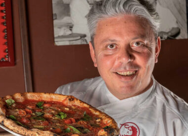This photo shows Vincenzo Esposito, with swept back graying hair, holding one of his famous Margherita pizzas.