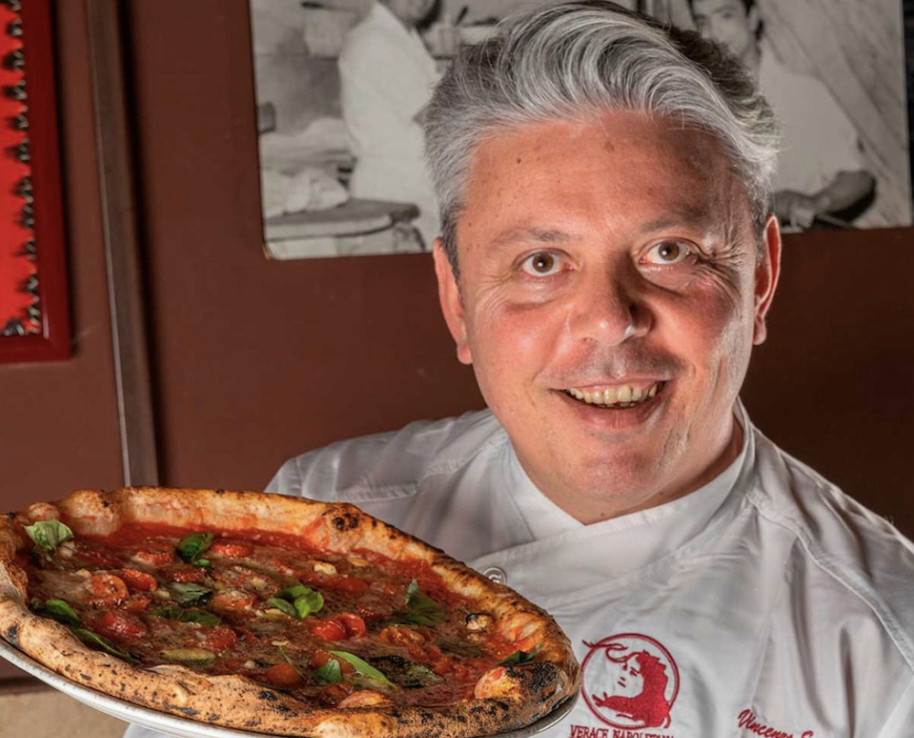 This photo shows Vincenzo Esposito, with swept back graying hair, holding one of his famous Margherita pizzas.