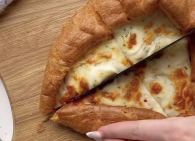 Photo shows someone cutting through a Yorkshire Pudding Pizza.
