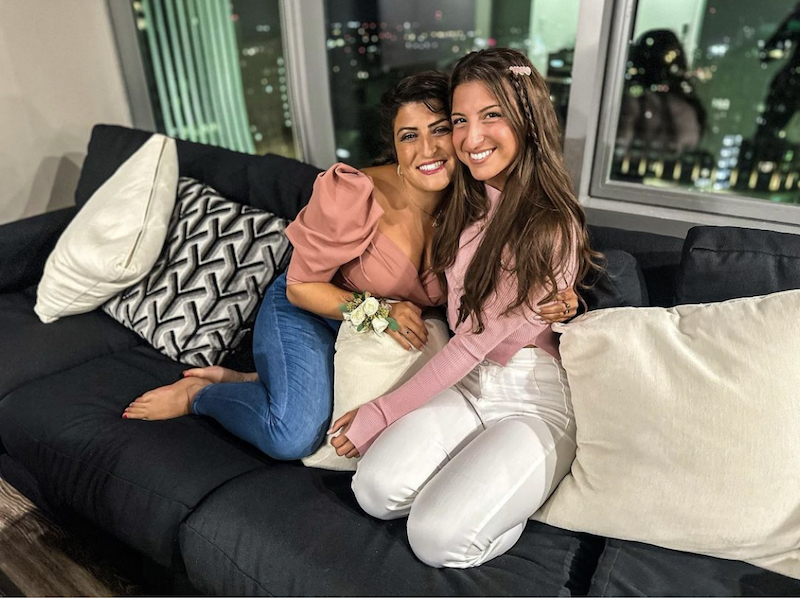 This photo shows Bianca and Giuliana sitting closely together on the couch with their arms around each other.