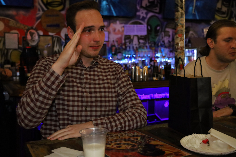 This photo shows a dark-haired man in a checkered shirt, his eyes teary and swollen, as he salutes. He was the contest's third place finisher.