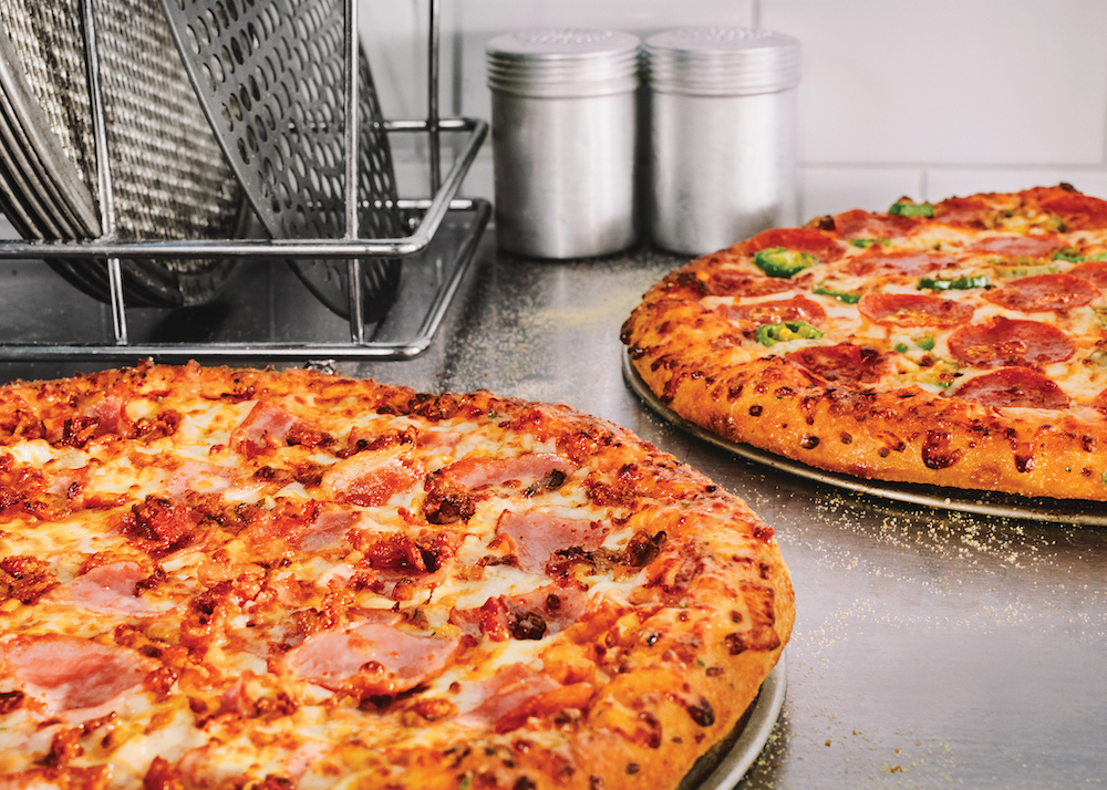 This photo shows two different types of medium-sized two-topping pizzas from Domino's. One is topped with ham and sausage, and the other is topped with pepperoni and jalapeños.