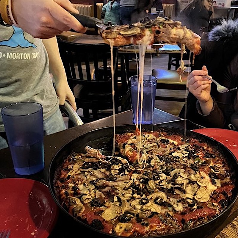 This photo shows a deep-dish pizza from Pequod's topped with mushrooms and black olives.