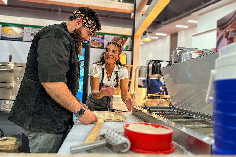 This photo shows Giuliana Calascibetta teaching a new employee how to make pizza.