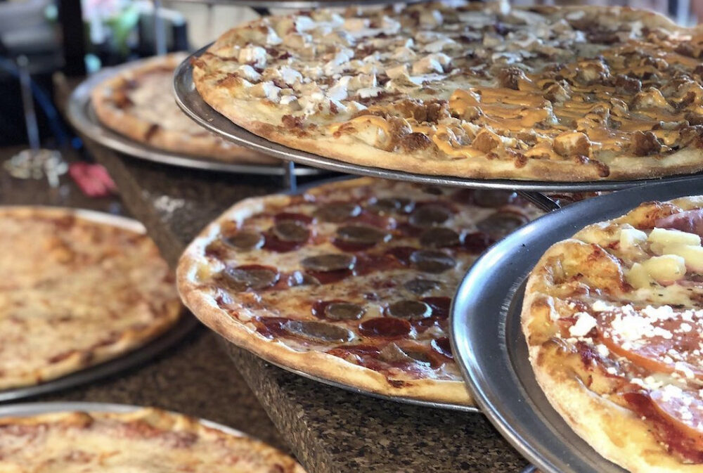 This photo shows a bunch of whole pizzas on a display rack at Brooklyn Joe's.