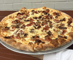 This photo shows a pizza topped with sausage and bacon from Jimmy's Pizza Cafe.