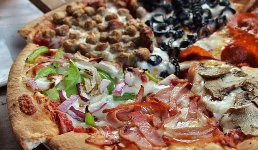 This photo shows a pizza with a different topping on each slice, such as pepperoni, sausage, black olives, bell peppers, etc.