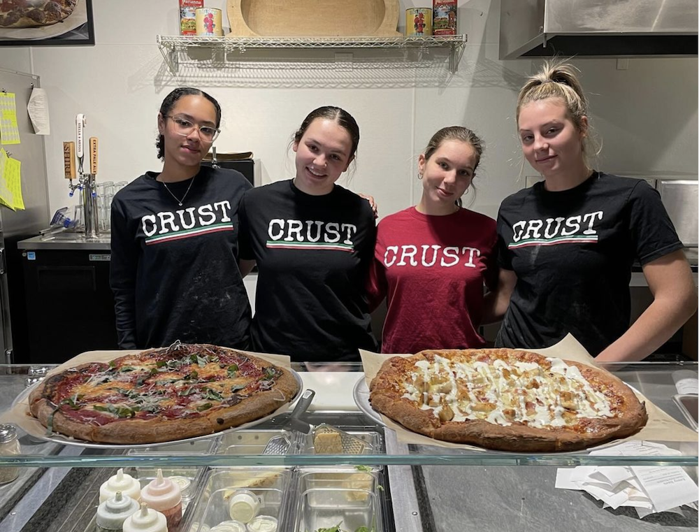 Staff at CRUST shows off a pair of pizzas. 