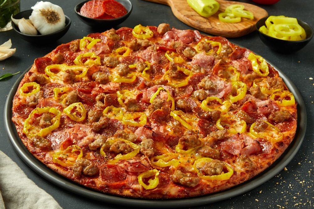 This photo shows a delicious-looking pizza topped with pepperoni, sausage and pepperoncinis.