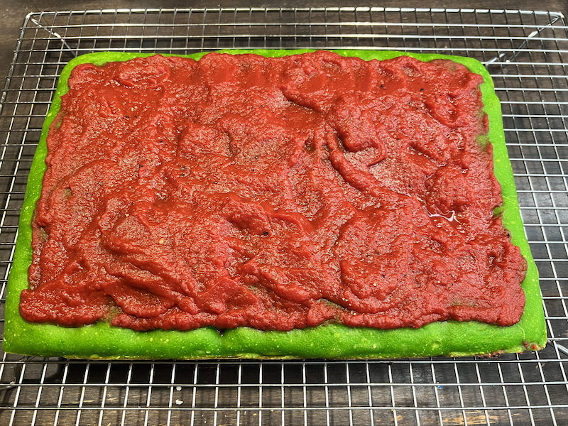 This photo shows the green crust piled with red tomato sauce