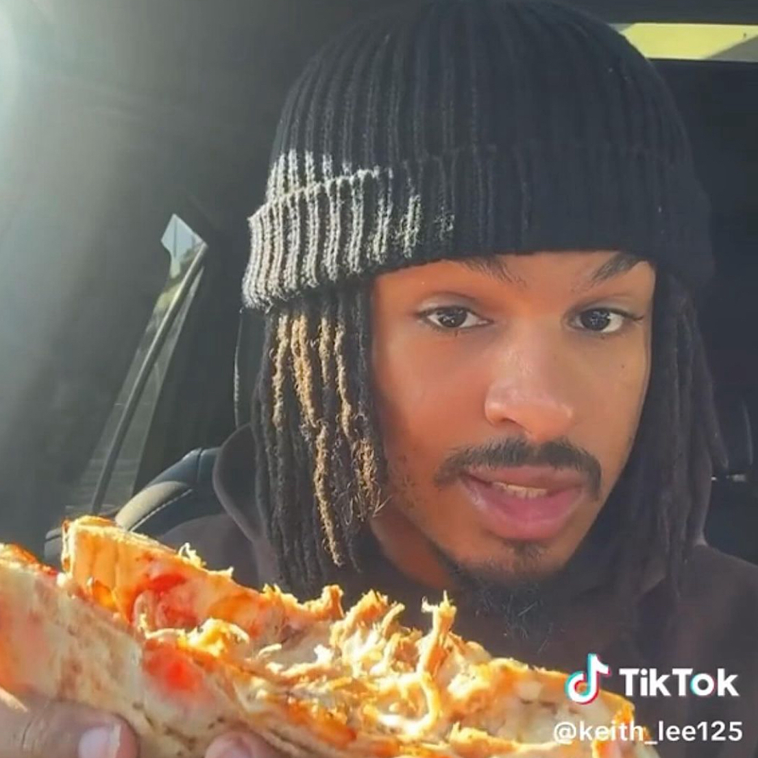 This photo shows Keith Lee eating a persil-topped pizza during a TikTok review.