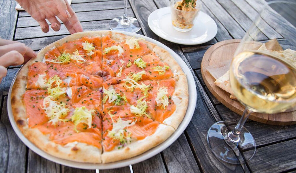 This photo shows a pizza topped with salmon and sour cream.