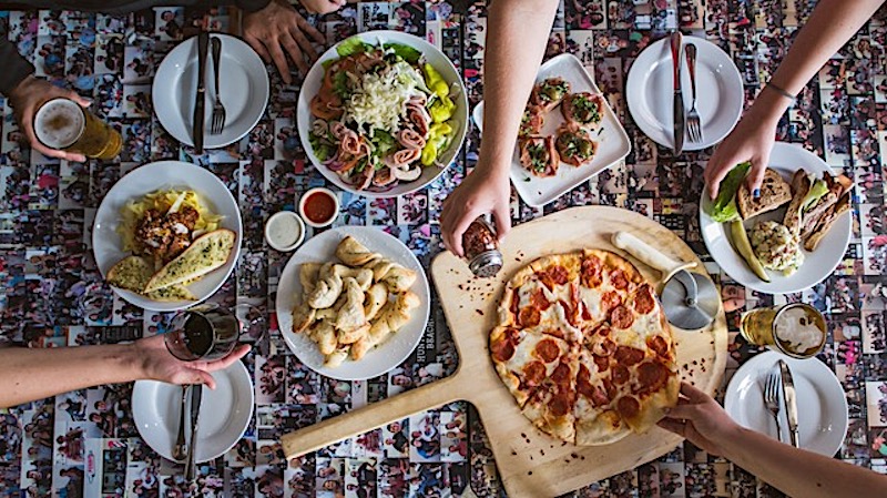 This photo shows a wide selection of Perry's menu items, including a pepperoni pizza, salad and appetizers.