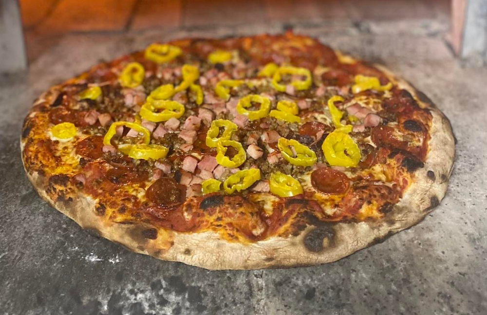 This photo shows a pizzz topped with diced Black Forest ham, pepperoni sausage and jalapeños.