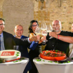 This photo shows four men and women sitting at a table with their glasses raised in a toast.
