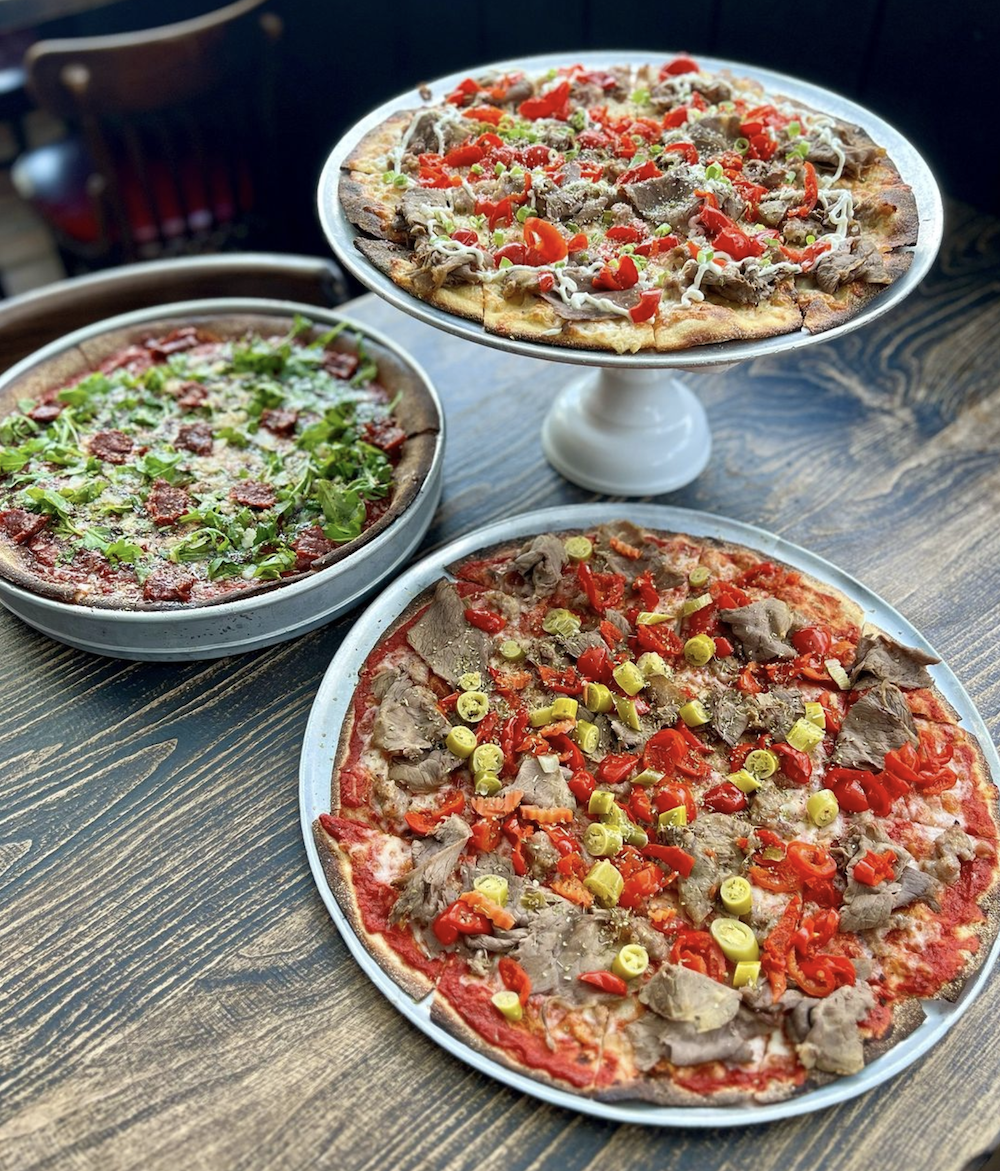 Three tavern-style pizzas on a table. 