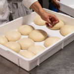 This photo shows 12 pizza dough balls in a white box