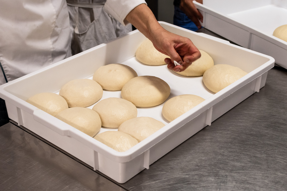 This photo shows 12 pizza dough balls in a white box