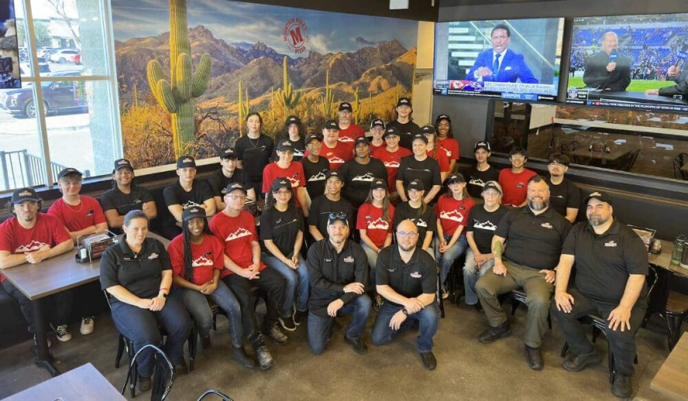 A group of employees gathers in a Mountain Mike's location to celebrate the store opening.