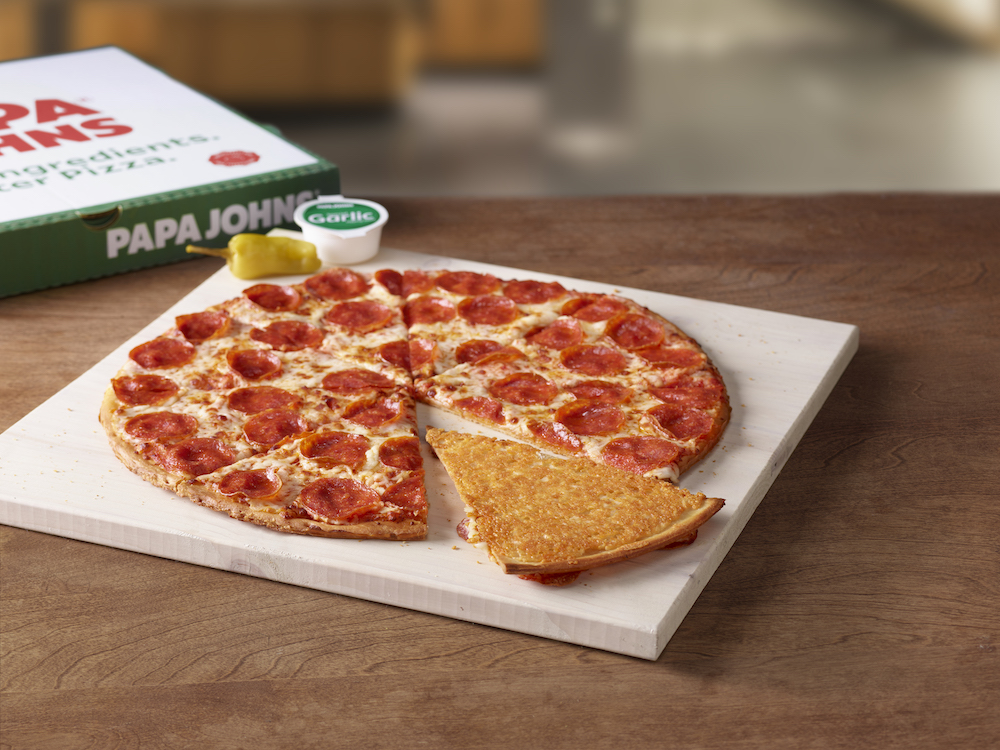 This photo shows a whole pepperoni pizza with one slice flipped over, revealing a cheese-crusted bottom.