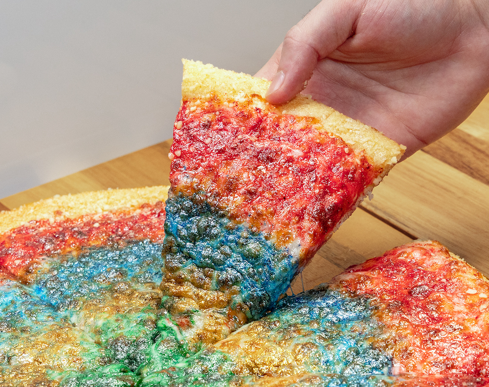 This photo shows an extremely colorful tie-dye pizza in red, blue, green and orange.