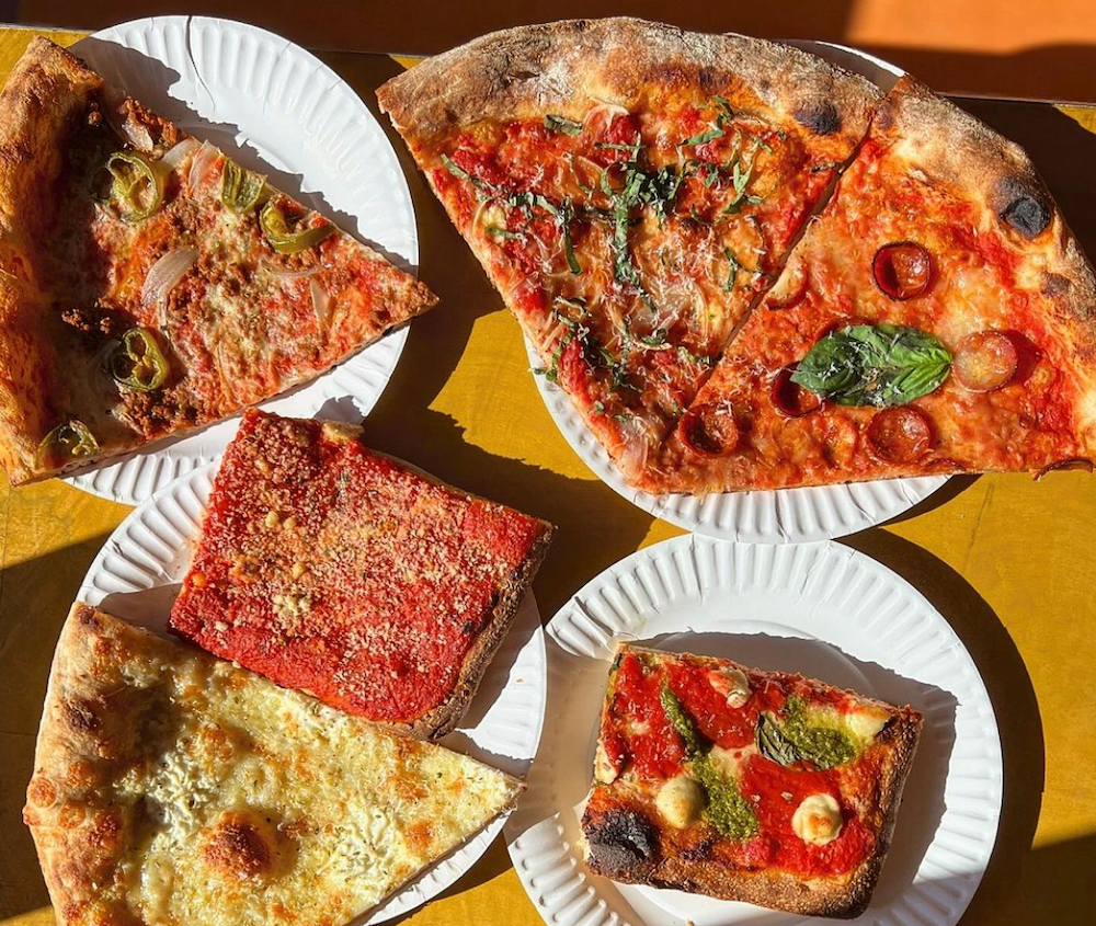 This photo shows a variety of vegan pizza slices, each on a paper plate.