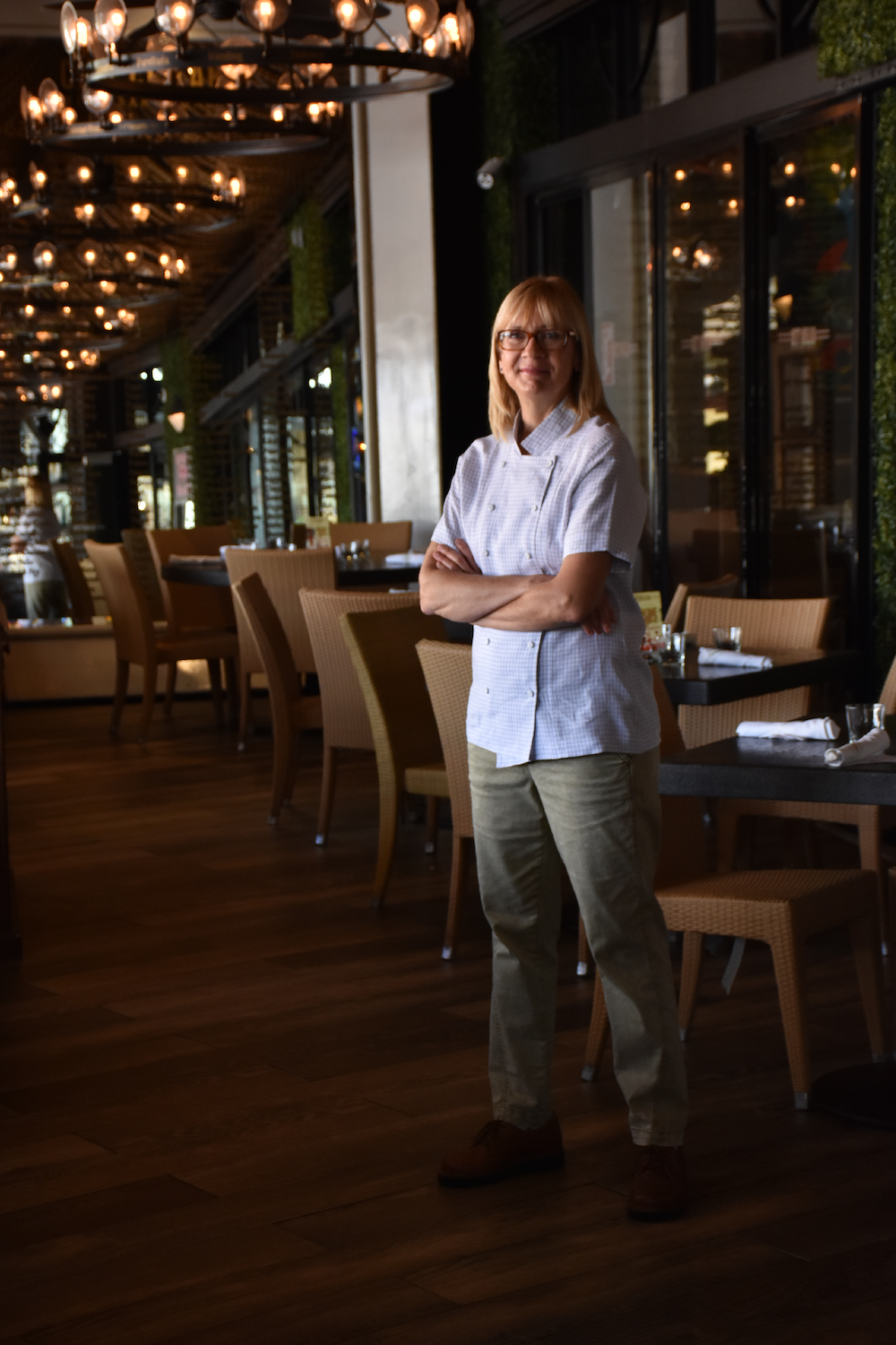 Lisabeth Summa, a chef, stands in her restaurant, Elisabetta's, with her arms folded. 