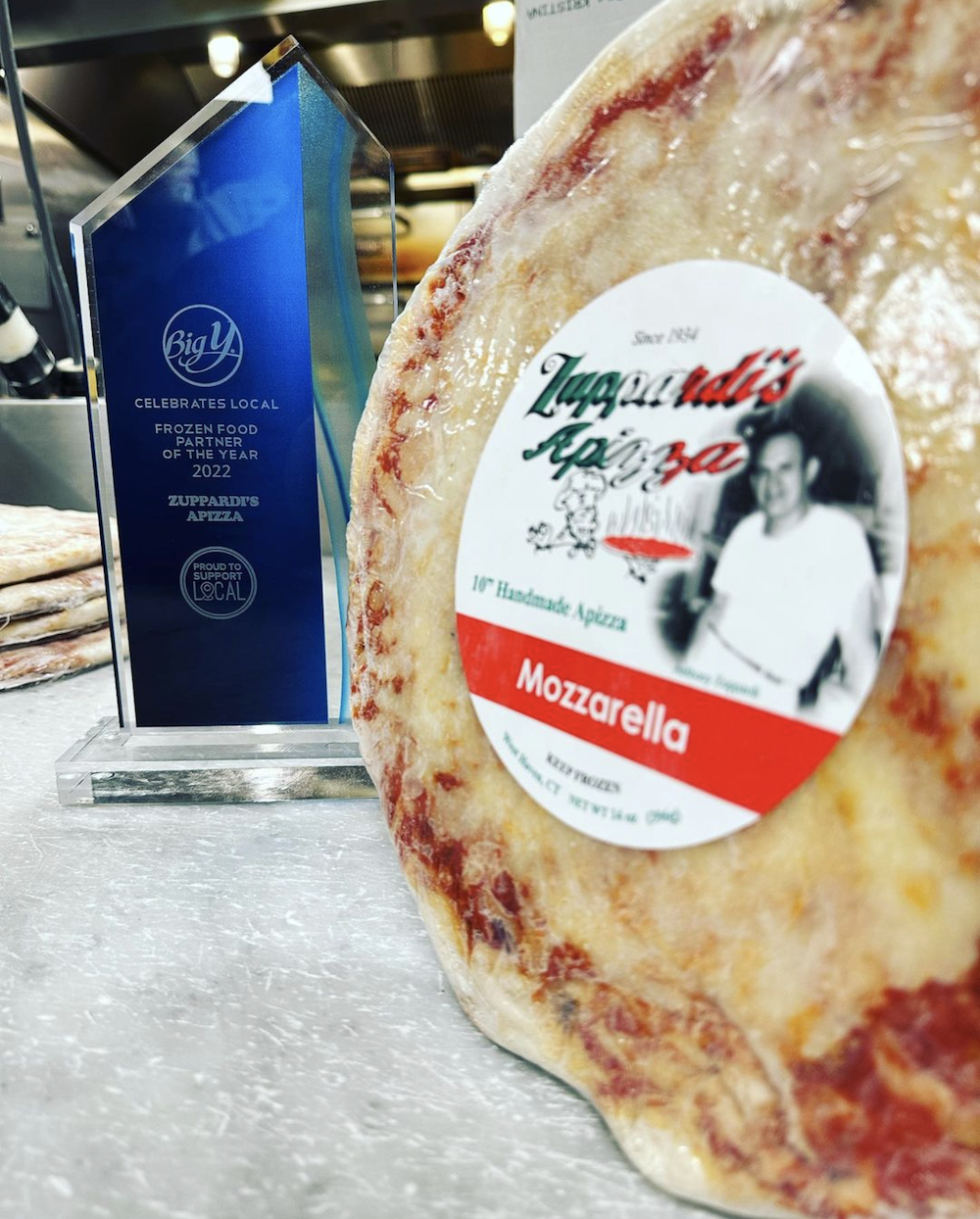 A frozen pizza made by Zuppardi's Apizza in West Haven, CT, sits next to a trophy commemorating an award won by Zuppardi's.