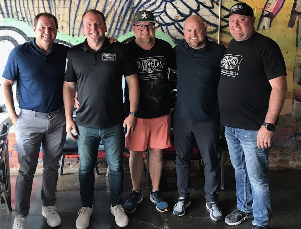 Five men stand in a pizzeria.