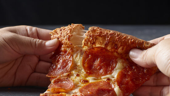 This photo shows a pair of hands tearing into the crust of Papa Johns' garlic parmesan pizza.