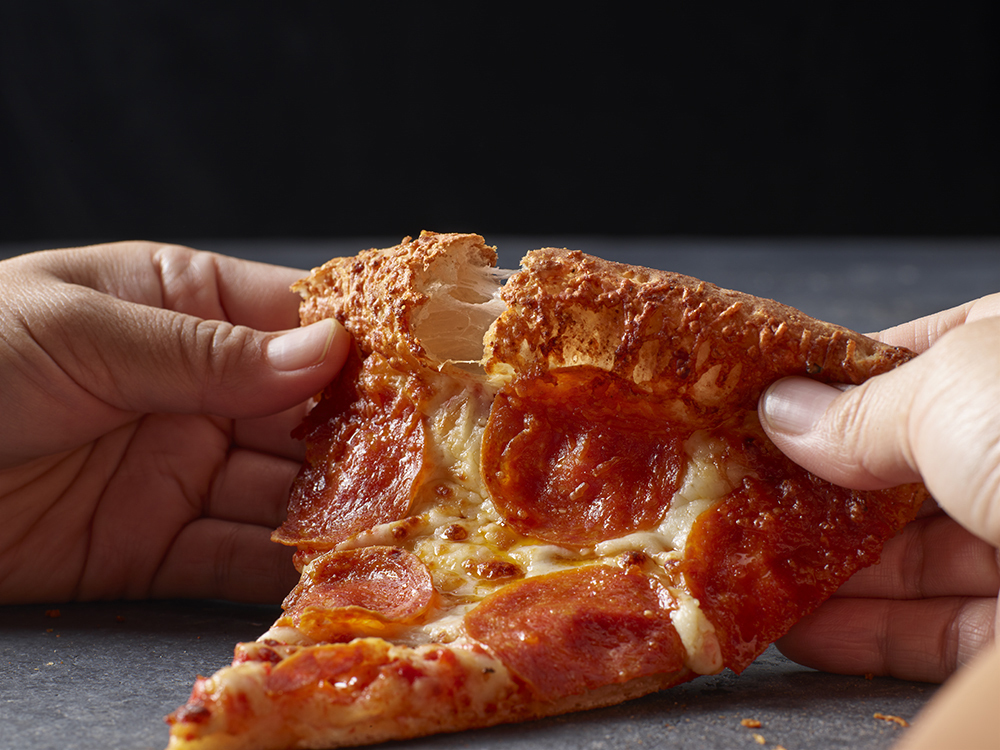 This photo shows a pair of hands tearing into the crust of Papa Johns' garlic parmesan pizza.