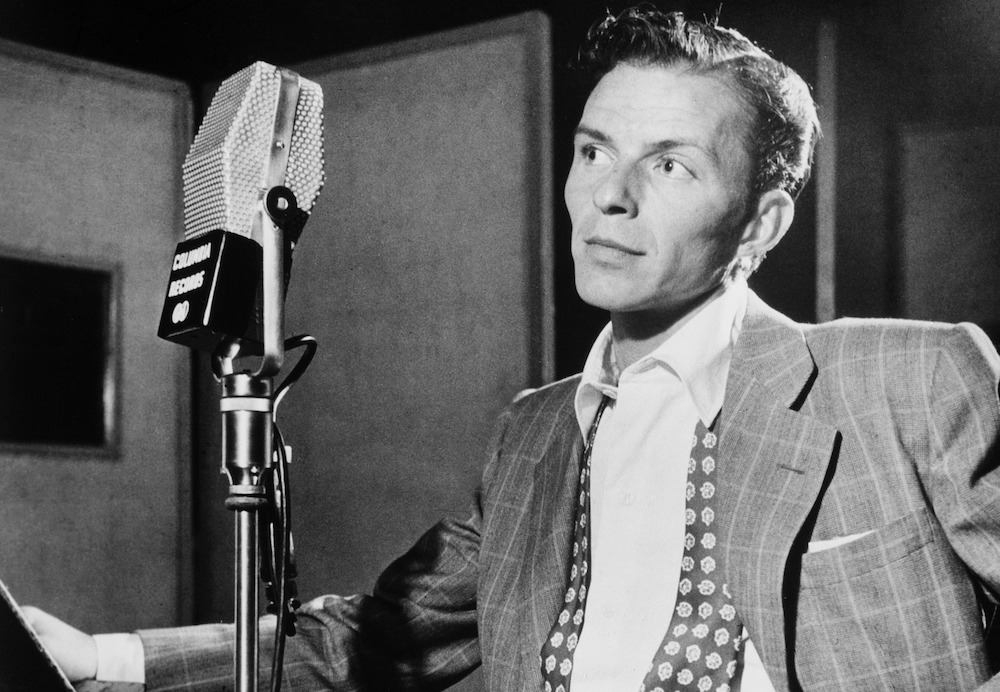 This photo shows a young Frank Sinatra standing in front of an old-school microphone.