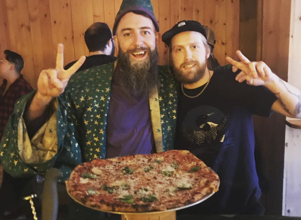 Josiah Bartlett, right, owner of Wizard Hat Pizza, poses with a friend at his old pizza pop-up home at Any Time bar in Brooklyn.