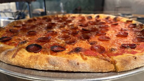 This photo shows the side view of a New York-style pepperoni pizza from Zazas Pizza.