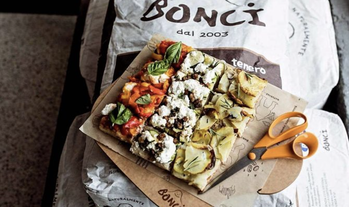 A variety of Roman-style pizza slices sit next to a pair of scissors that was used to cut them.