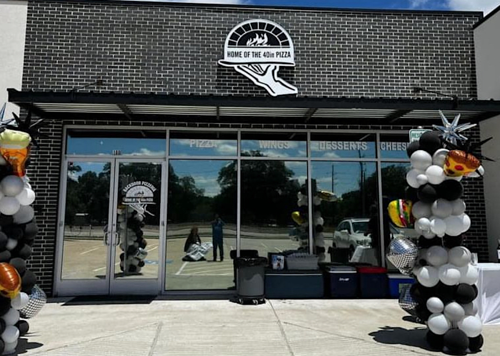 This photo shows the exterior of Backdoor Pizzeria with balloons on either side of the walkway heading toward the building.