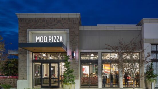 This photo shows a brightly lit MOD Pizza location against a dark blue backdrop.