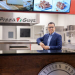 Shahpour Nejad poses behind the counter at Pizza Guys, the pizza franchise that he owns.