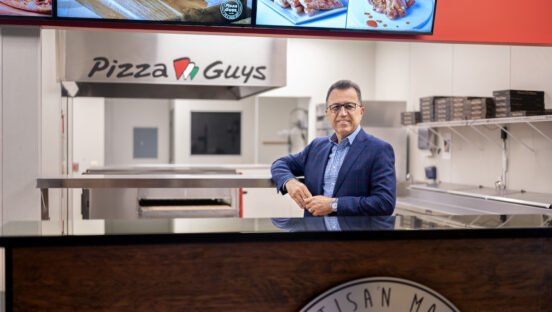 Shahpour Nejad poses behind the counter at Pizza Guys, the pizza franchise that he owns.