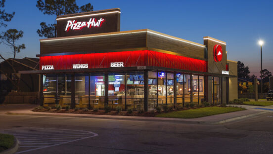 This photo shows the exterior of a Pizza Hut restaurant against a dark blue background.