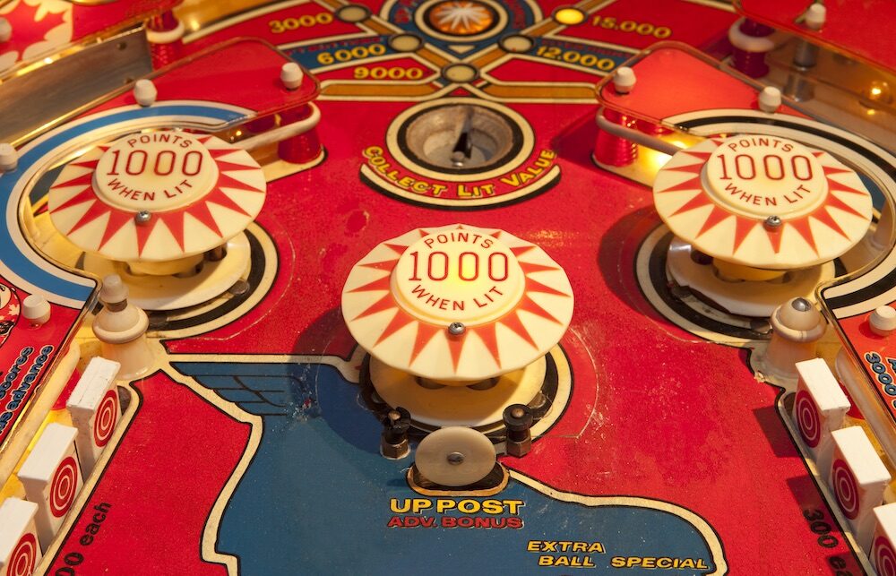 This photo shows the various beige-colored targets (with red lettering) on a pinball machine with a red board