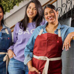 This photo shows three dark-haired women standing together and smiling.