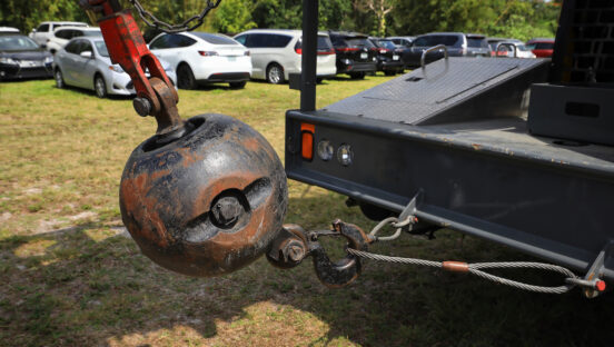 This photo shows a close up of a metal wrecking ball at the back of a crawler crane.