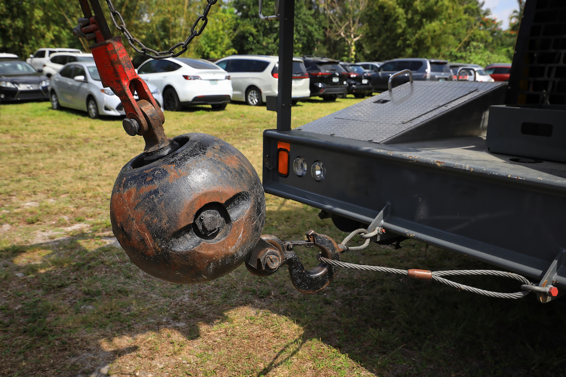 This photo shows a close up of a metal wrecking ball at the back of a crawler crane.