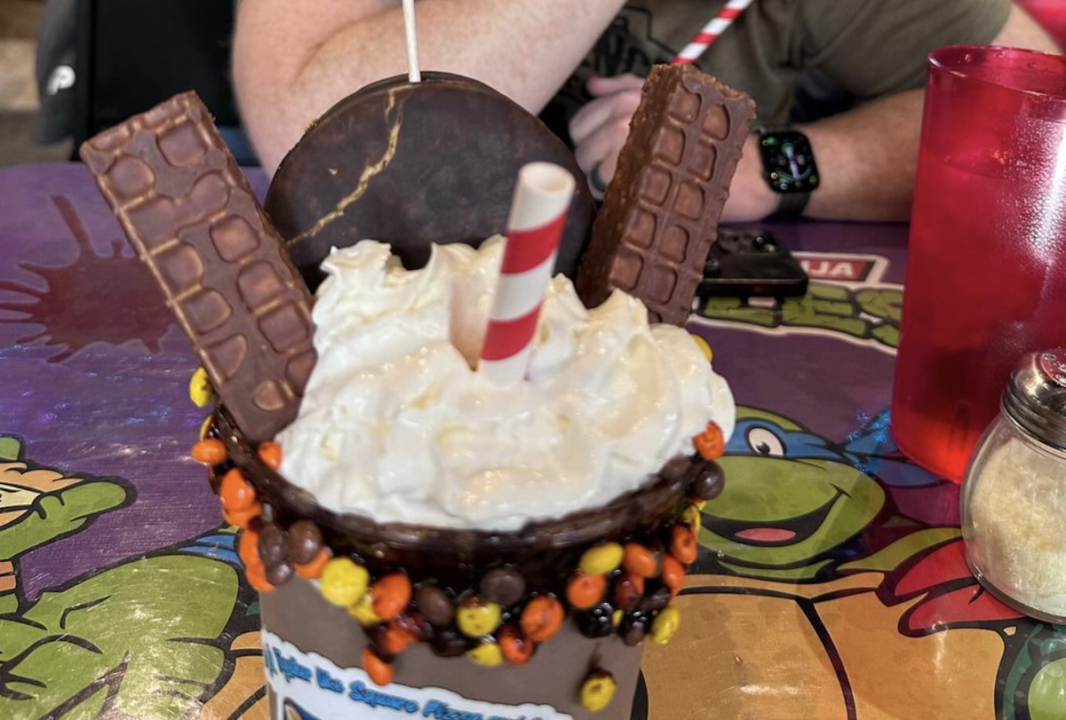 A milkshake with a mini waffle and donut sticking out of the whipped cream on top.