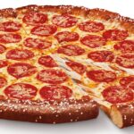 This photo shows a whole pepperoni pizza with one slice pulled out slightly.