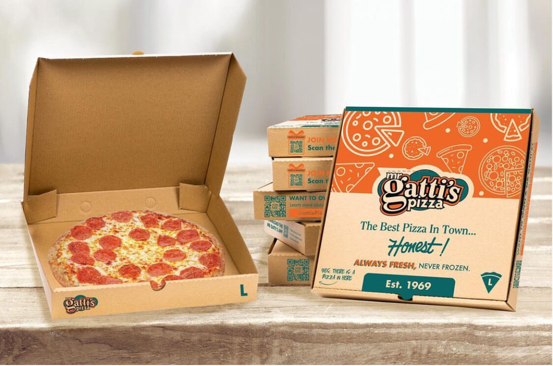This photo shows an opened pizza box with a pepperoni pizza inside as well as another closed pizza box next to it.